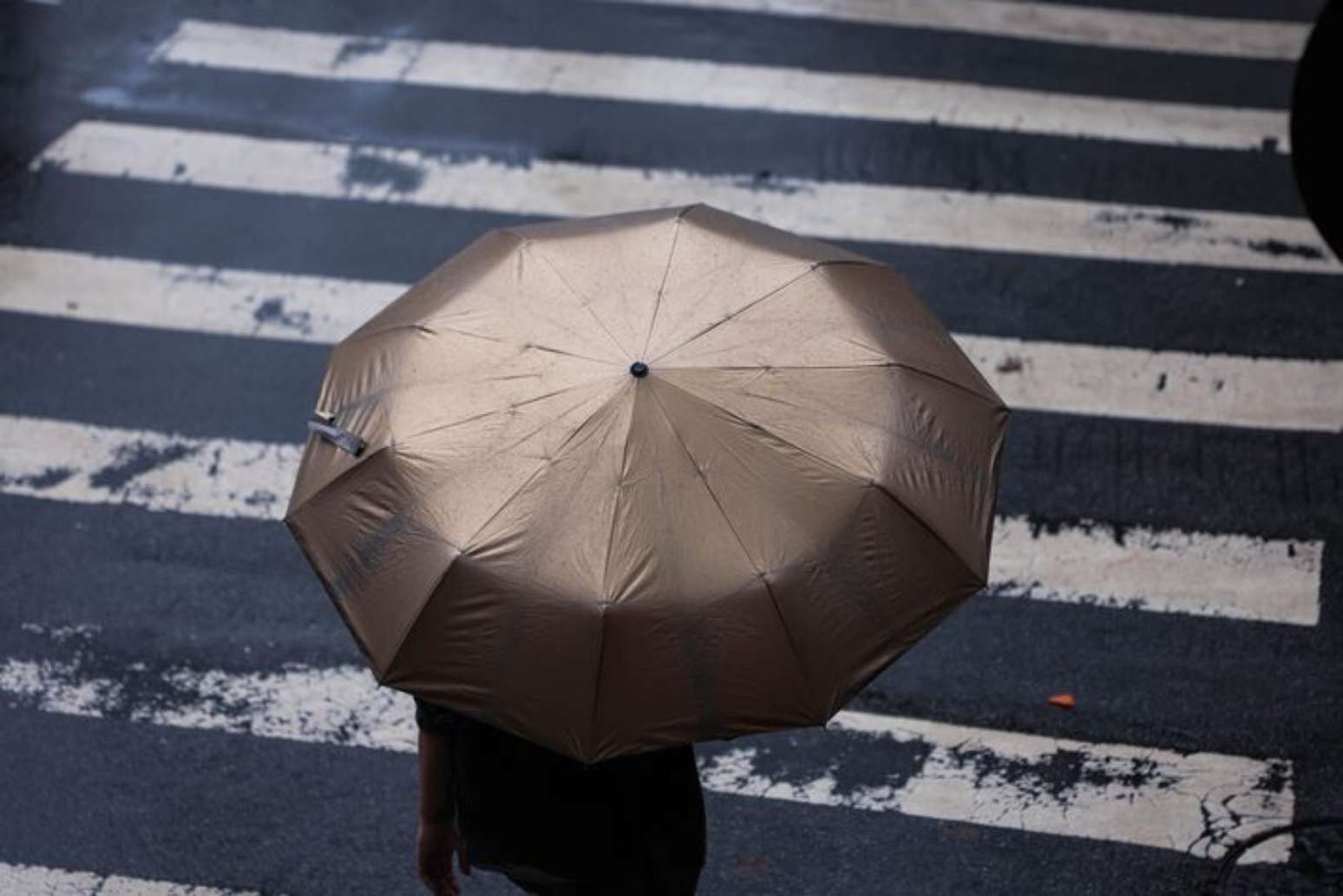 Pedestres enfrentam a chuva com seus guarda-chuvas e capas nas esquinas da Rua Joaquim Antunes e Arthur de Azevedo, no bairro de Pinheiros, zona oeste da cidade.