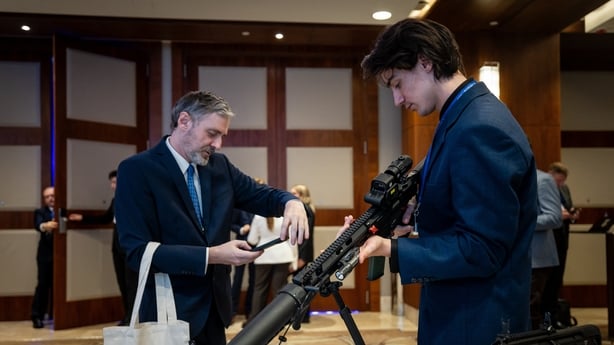 Participants inspect a weapon displayed at a stand during the second day of Warsaw Security Forum in Warsaw, Poland on October 13, 2026. (Photo by Wojtek RADWANSKI / AFP)