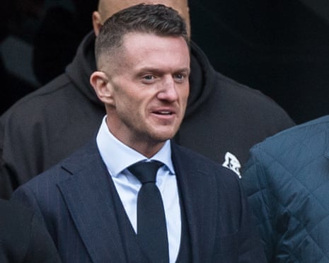Tommy Robinson arrives at Southwark crown court: he is wearing a dark suit and tie, and is flanked by burly men taller than himself.